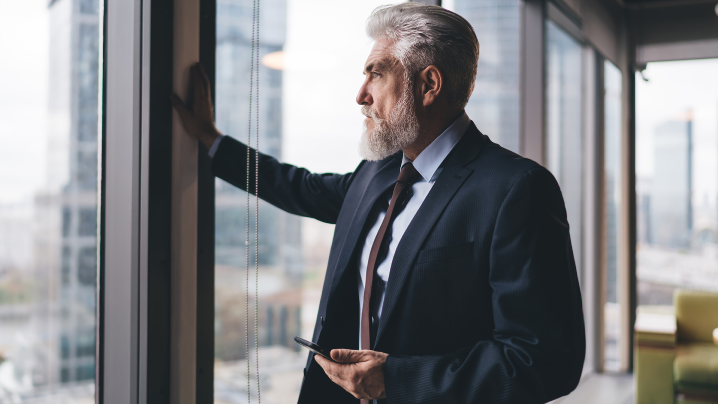 man looking outside through window with emotional deal success